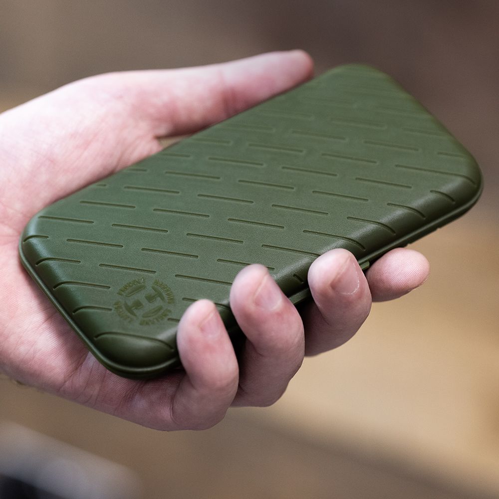 Étui à fléchettes Harrows Slimcase Eine Hand hält ein schlankes, grünes Etui. Das Etui hat ein strukturiertes Muster und ein rundes Logo in der Ecke.