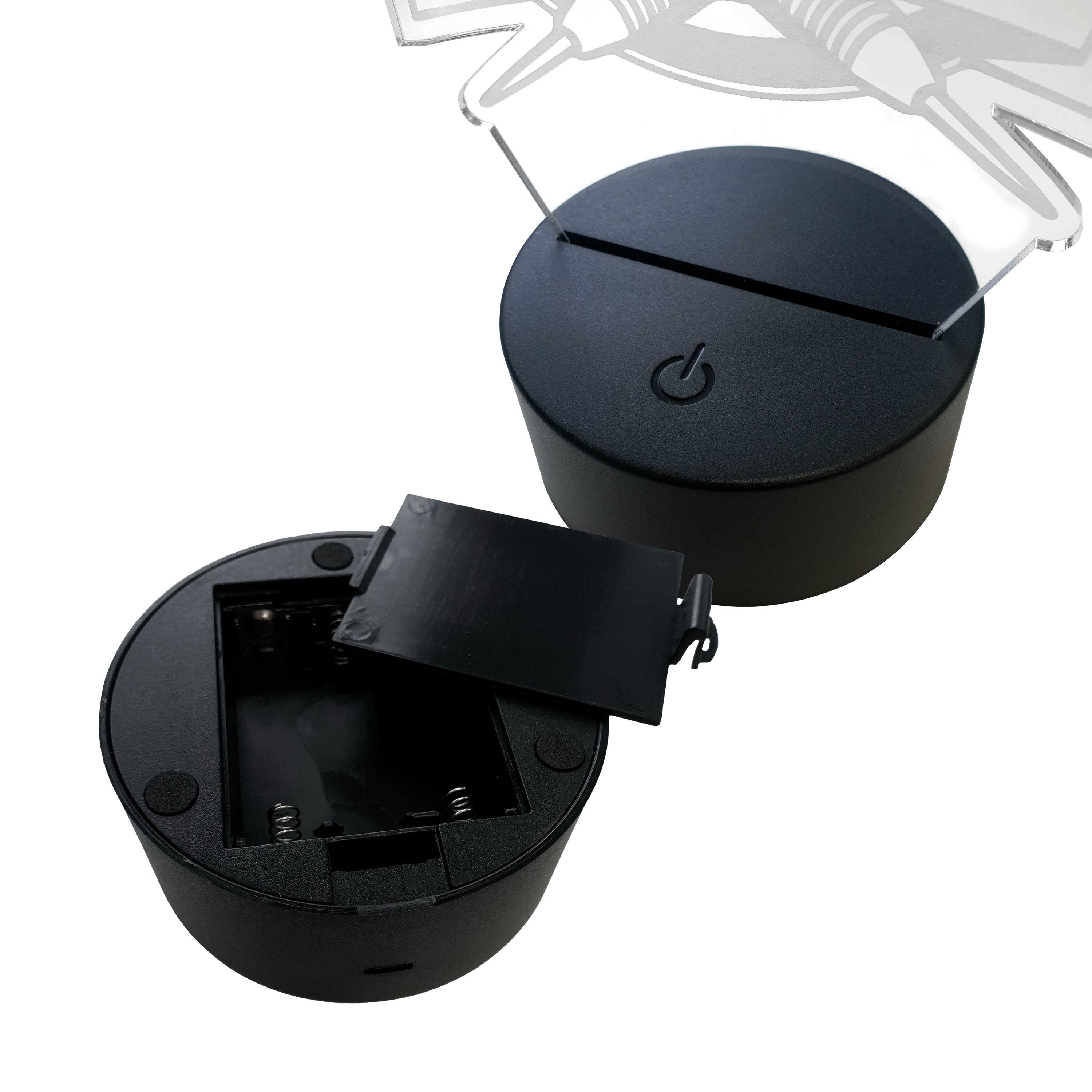 Lampa rzutkowa LED z pleksiglasu z niestandardowym tekstem Das Bild zeigt zwei runde LED-Lampen-Sockel aus schwarzem Kunststoff. Einer der Sockel hat ein offenes Batteriefach, der andere ist mit einer Plexiglasplatte bestückt.