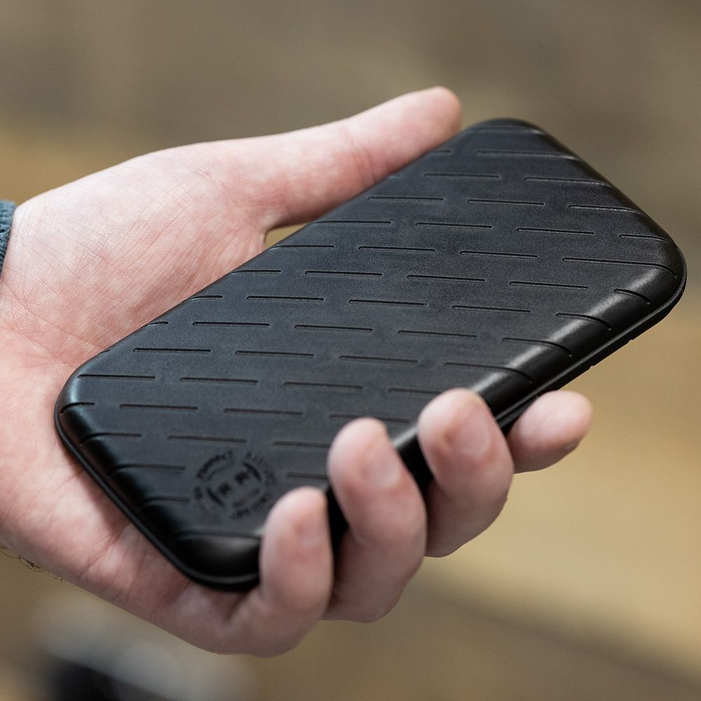 Custodia per freccette Harrows Slimcase Eine Person hält eine schwarze, schlanke Darttasche in der Hand. Die Oberfläche der Tasche hat ein dezentes, gerilltes Muster.