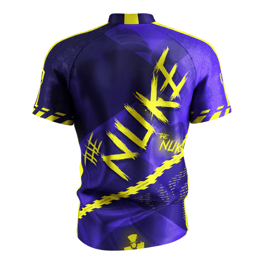 Camiseta de dardos Target Coolplay Luke Littler 2025 Das Bild zeigt das „Target Coolplay Luke Littler 2025 Dartshirt“ von hinten. Das Shirt ist überwiegend lila mit auffälligen gelben Designs und dem Schriftzug „NUKE“ auf dem Rücken.
