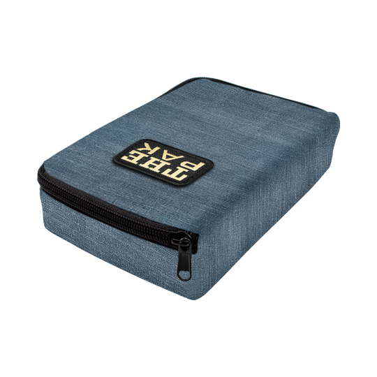 715TP_The_PAK_Jeans_Editon_Darttasche_2 Die Abbildung zeigt die "The Pak Jeans Edition Darttasche" in einem blauen Jeans-Design. Auf der Vorderseite befindet sich ein aufgenähtes Label mit der Aufschrift "THE PAK" und ein schwarzer Reißverschluss.