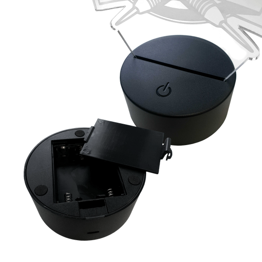 Lampa rzutkowa LED z pleksiglasu z niestandardowym tekstem Das Bild zeigt zwei runde LED-Lampen-Sockel aus schwarzem Kunststoff. Einer der Sockel hat ein offenes Batteriefach, der andere ist mit einer Plexiglasplatte bestückt.